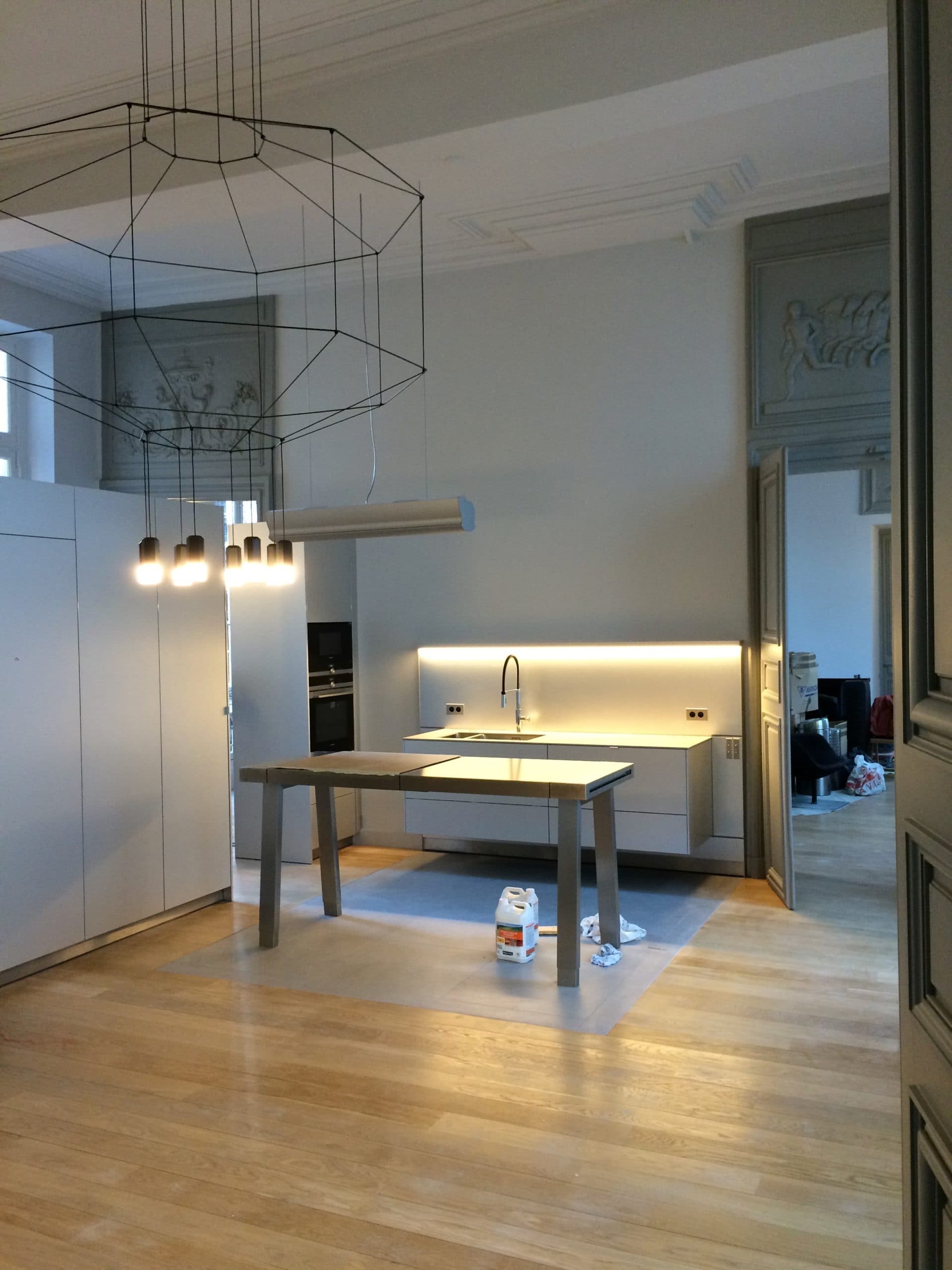 Cuisine d’architecte ouverte dans un loft du Marais à Paris avec îlot central et gorges lumineuses